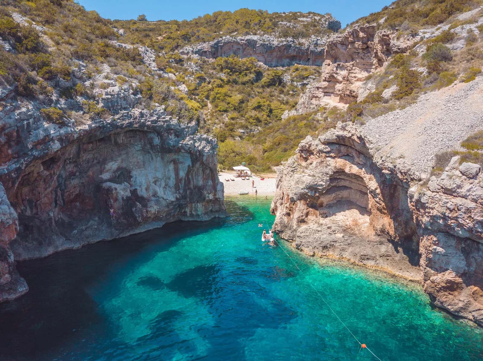 Boat anchored in a dramatic cliff-lined turquoise cove on the Adriatic