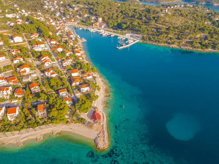 Aerial view of a sheltered bay with a speedboat cutting across clear water