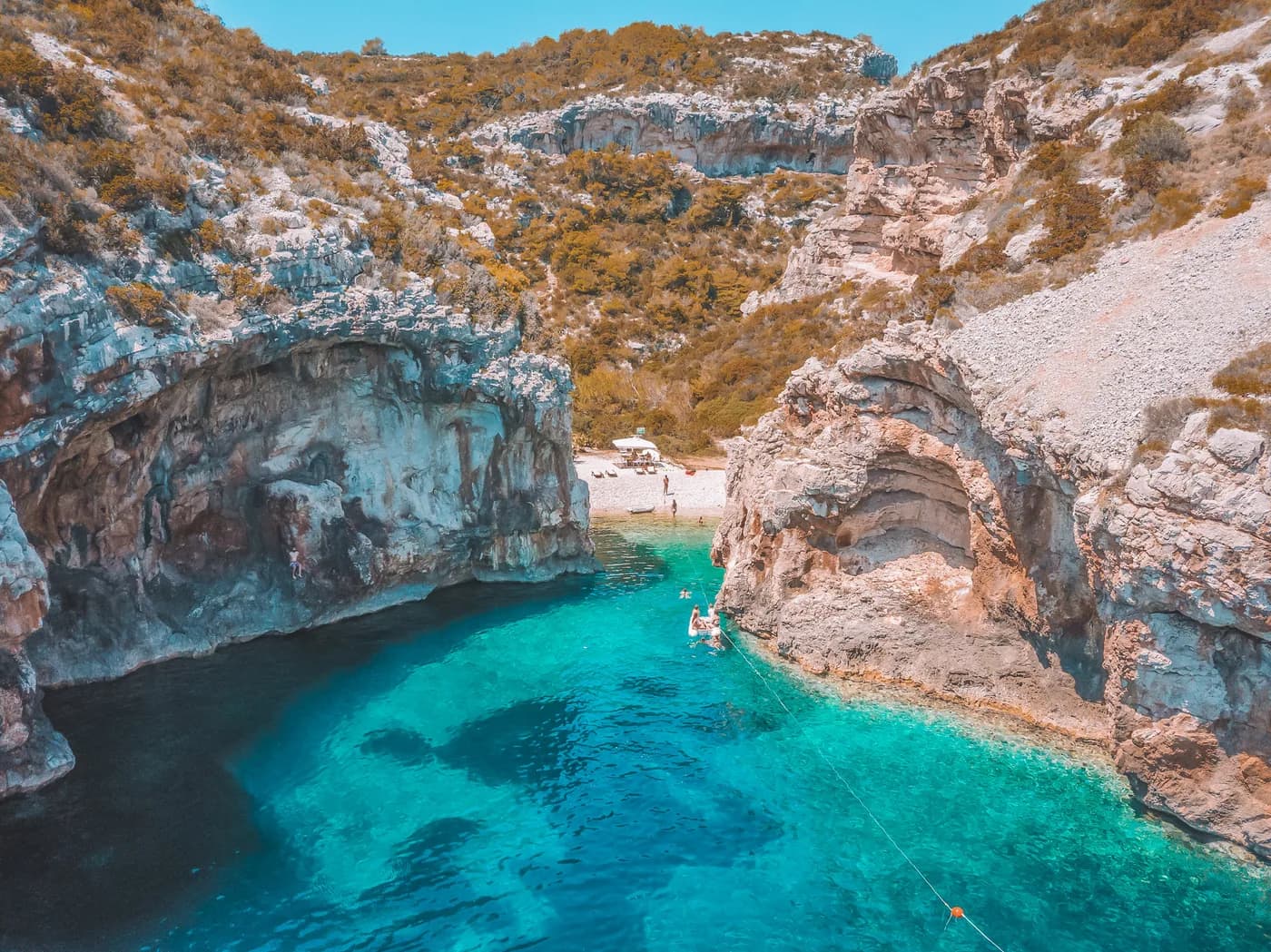 Boat in a dramatic cliff-lined turquoise cove near Vis